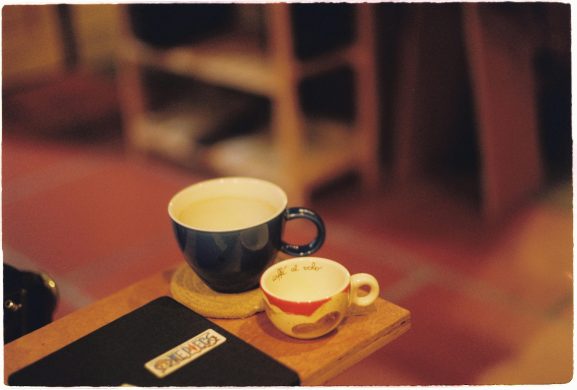 Warm and cozy setup with coffee cups on a wooden table in a rustic cafe setting.
